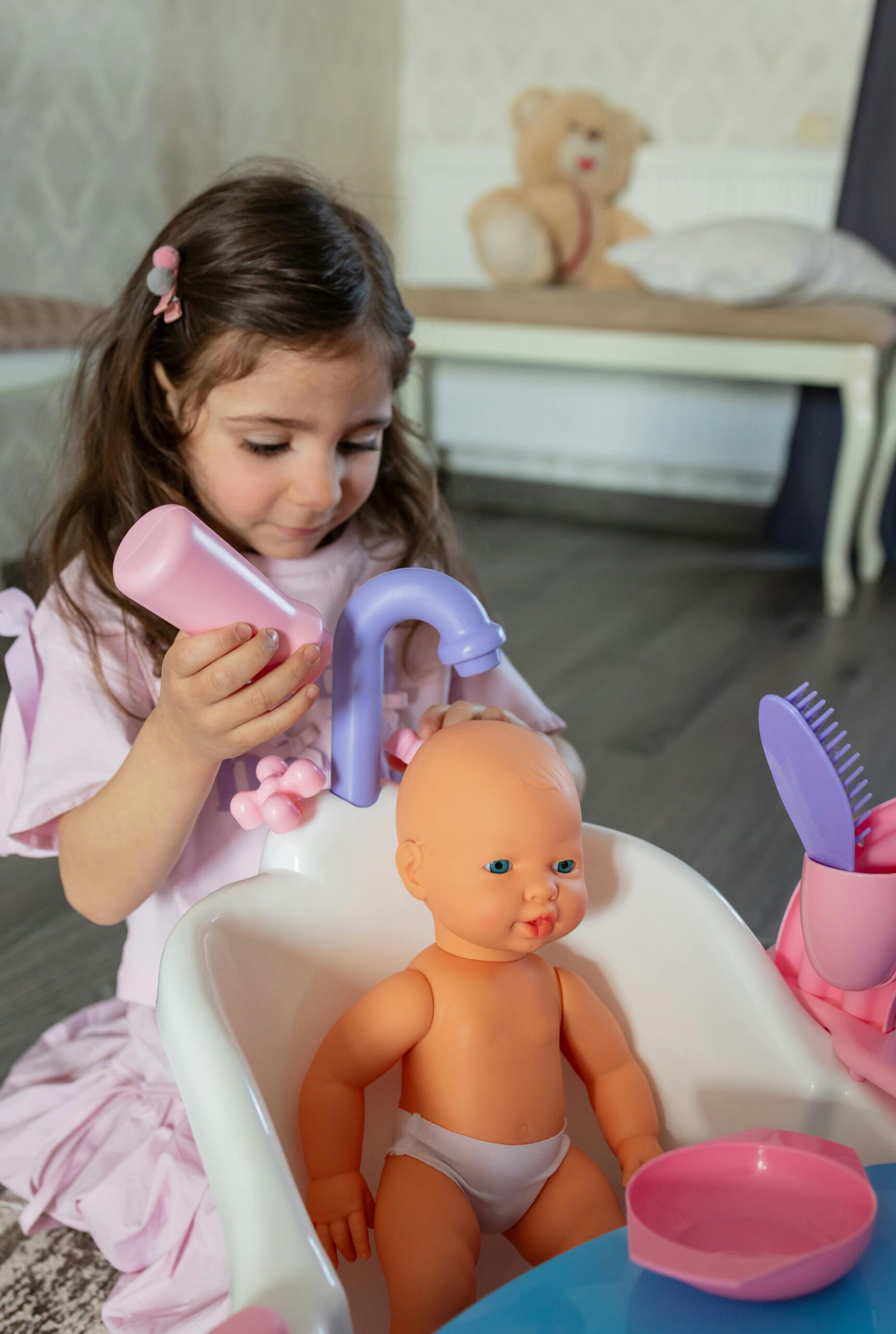 A young girl engages in imaginative play with a doll in a colorful toy bathtub indoors.
