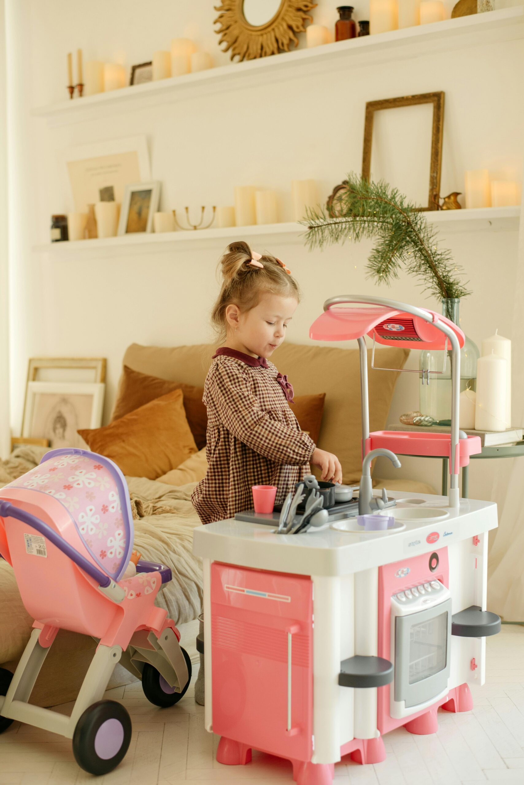 Young girl playing with a toy kitchen set in a cozy bedroom setting, expressing childhood fun.